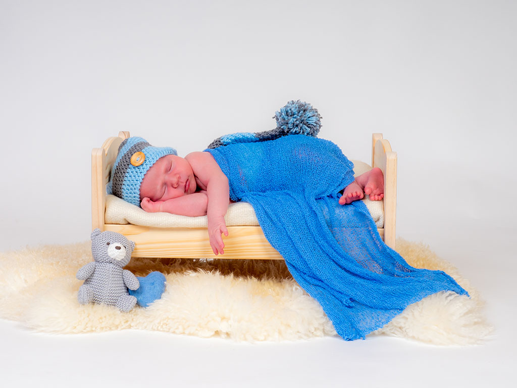 newborn baby asleep on bed taken by newborn photographer in Braintree